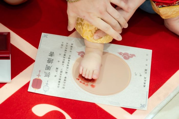 「抓周」是華人傳統育兒文化中的一種周歲儀式，通常在寶寶滿一歲時舉行。家長會在孩子面前擺放各種具有象徵意義的物品，讓孩子自由抓取，藉此象徵孩子未來的興趣、個性或發展方向，也代表家人對孩子成長的祝福與期待。  常見抓周物品例如：  書本：象徵聰明、愛讀書 算盤／錢幣：象徵財富、理財能力 麥克風：象徵表達能力、表演天分 畫筆：象徵藝術創作 醫療器具：象徵醫護相關志向 球類：象徵運動天分  現代的抓周活動，除了保留傳統文化意義，也結合親子互動、拍照紀念與家庭儀式感，因此成為許多年輕家庭喜愛的重要成長活動之一。
